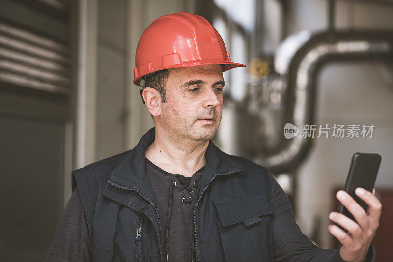 在工厂里使用手机的男性技术员