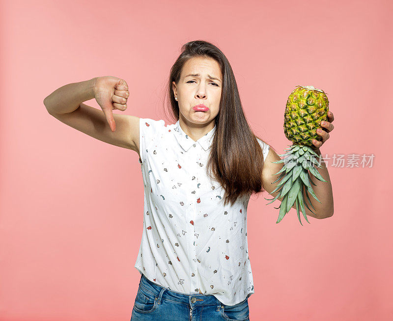 不高兴的年轻女子拿着一个成熟的菠萝