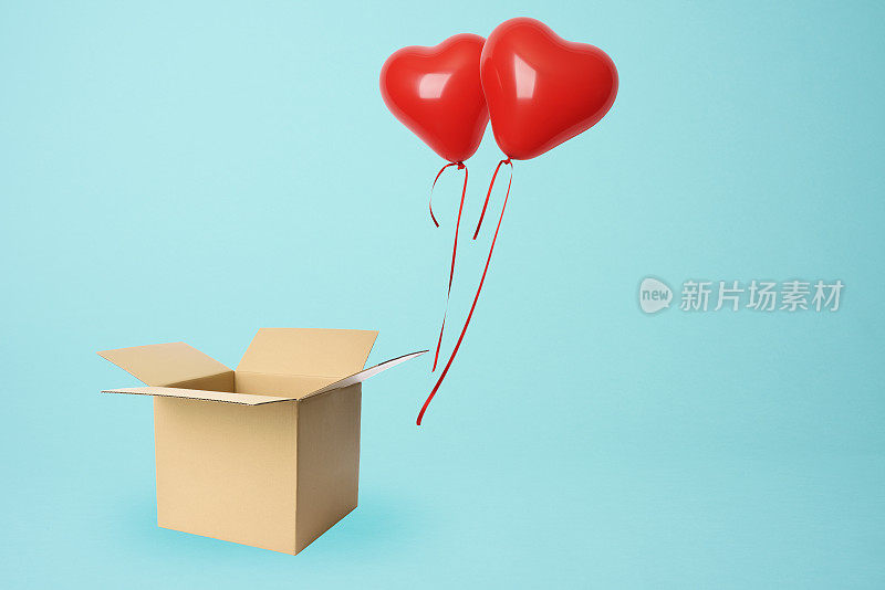两个红色的心形气球漂浮在一个纸板箱上