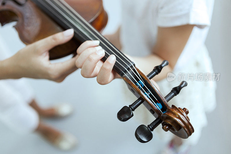 老师的手帮助孩子的手拉小提琴