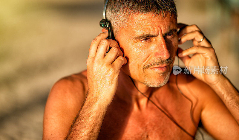 听音乐。英俊的男人在海滩上听音乐度假