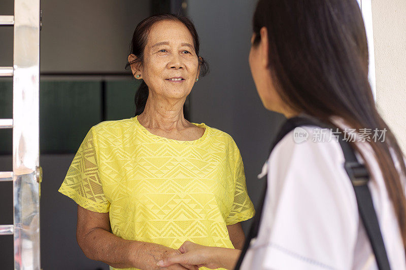 资深亚洲妇女在房子门口迎接保险代理人