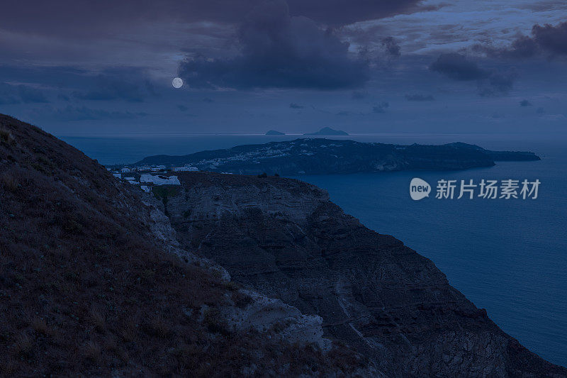 这是希腊圣托里尼岛基克拉迪斯岛悬崖顶上拍摄的海面上满月的数字合成图像，俯瞰着火山口。