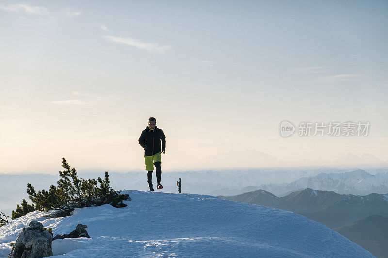 黎明时分，一名徒步运动员爬上雪山的山脊