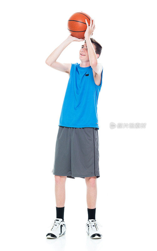 白人年轻男性篮球运动员站在白色背景前，拿着篮球和使用运动球