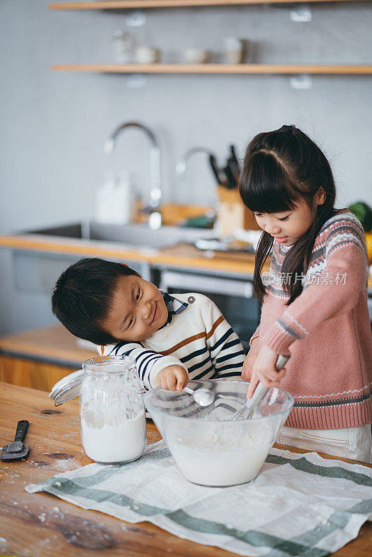 快乐的小女孩和小男孩在厨房里一起做饼干