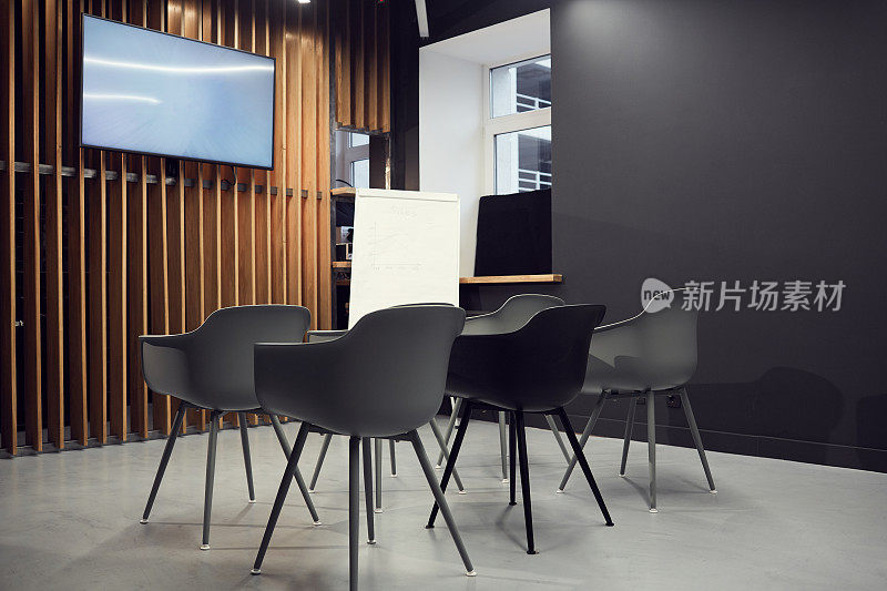 空荡荡的小会议室，灰色的办公椅靠在等离子屏幕和白板上
