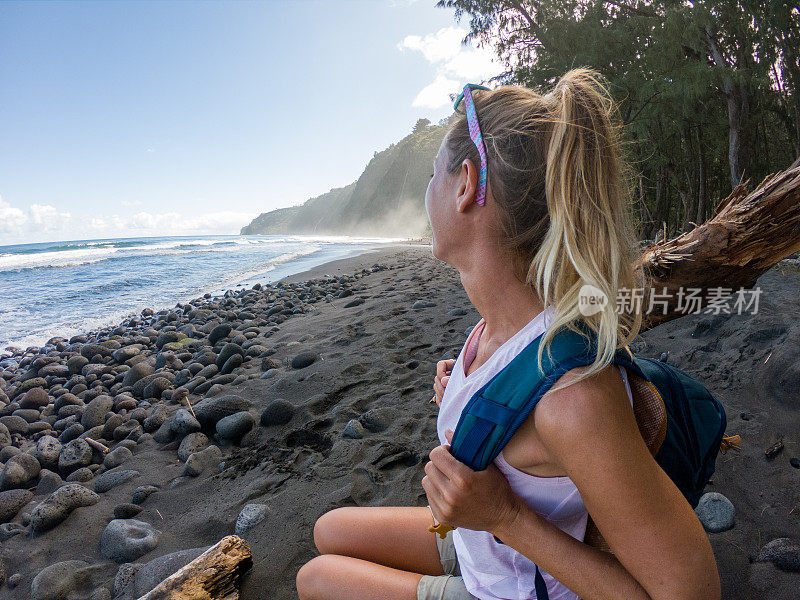 在夏威夷海滩上，徒步旅行的女人在瞻望Waipio山谷