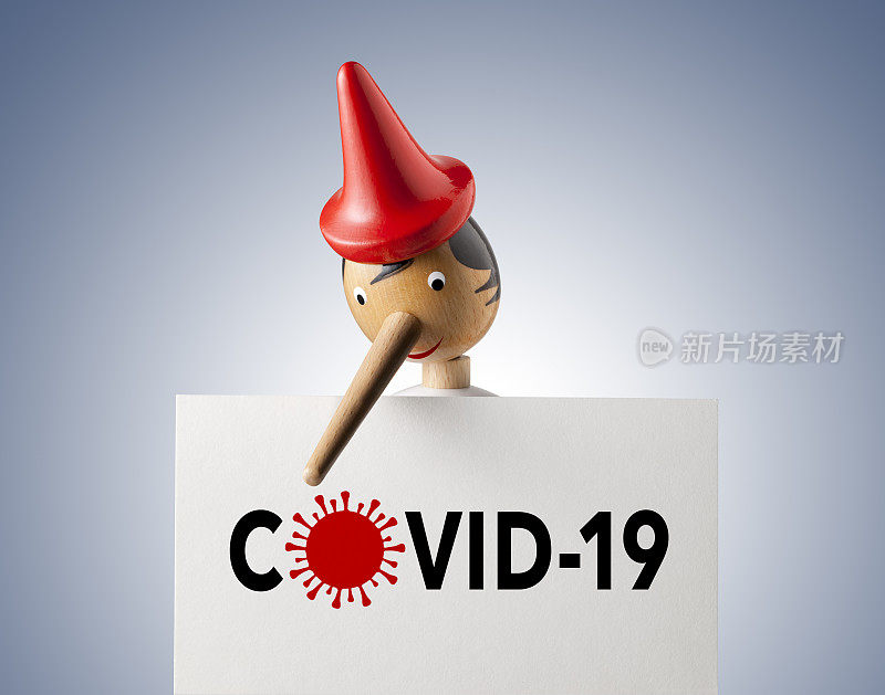 冠状病毒的谎言。皮诺曹俯视着一张写着Covid-19字样的纸。