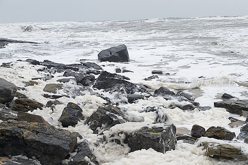 海浪的泡沫冲到多岩石的海岸上