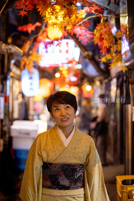 身着和服的日本妇女走在日本居酒屋小巷的秋天