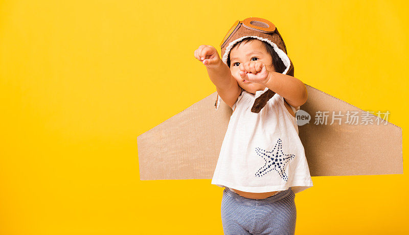 小孩小男孩微笑着戴着飞行员帽玩，护目镜和玩具纸板飞机机翼