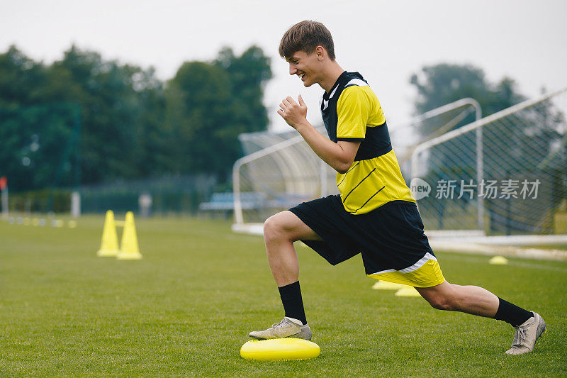 平衡垫的稳定性足球训练。运动平衡训练。年轻足球运动员提高技术。球员在场上训练。草足球场。指导户外足球设备