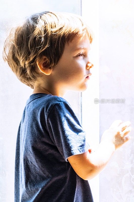 一个沉思的小男孩望着窗外