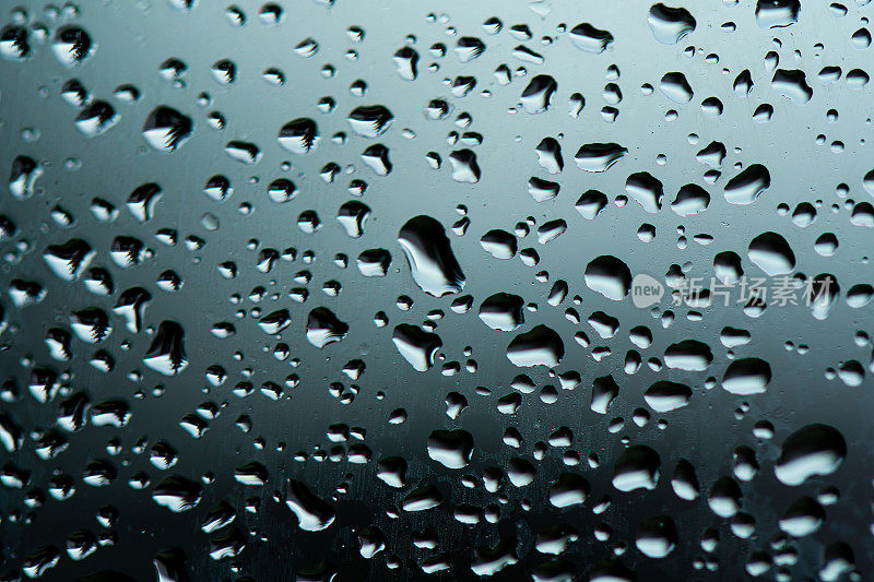 微距雨滴蒸气落在窗玻璃上。雨滴落在窗玻璃表面。透过窗户观看。雨滴落在玻璃上。水模式结构