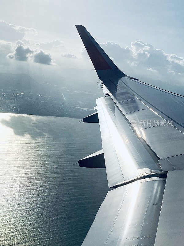 飞机机翼在天空中飞行与海洋和天空的背景