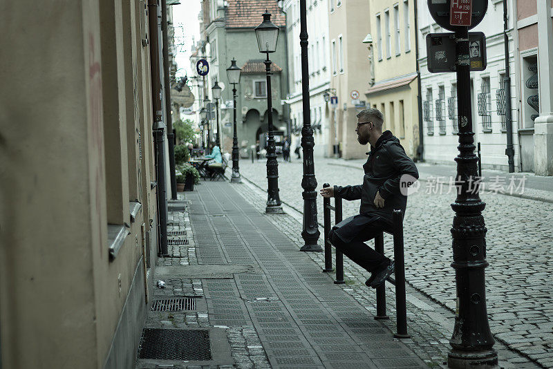 在市中心的波兰老城，一名男子坐在一所房子的入口处抽烟。