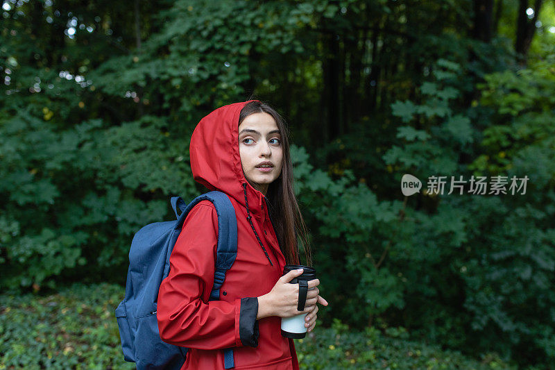 穿着红色雨衣的年轻女子在大自然中徒步旅行