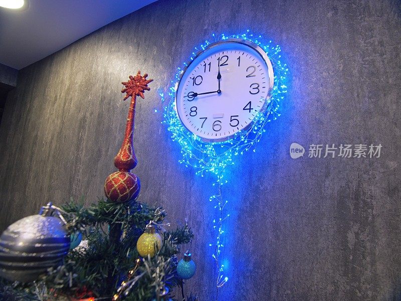钟和圣诞树，球，玩具。间隔拍摄。钟挂在墙上。时钟上的时间是23点45分到0点。