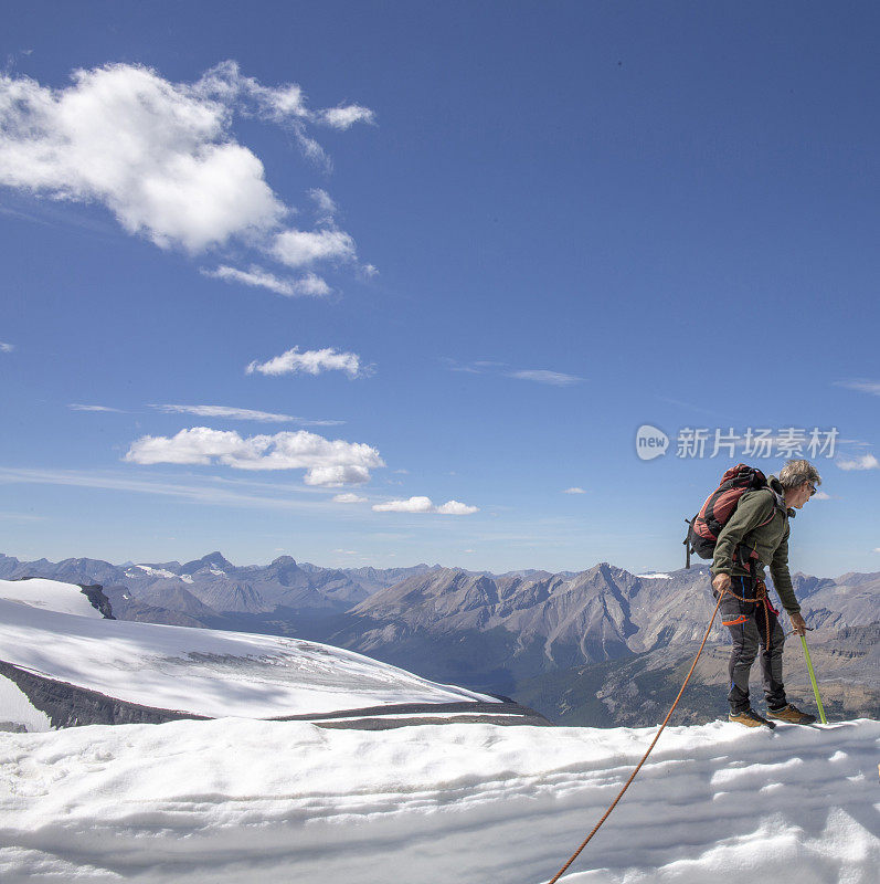 一位男性登山运动员到达了雪山的顶峰