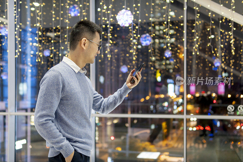 一名亚洲男子在市中心用手机拍照