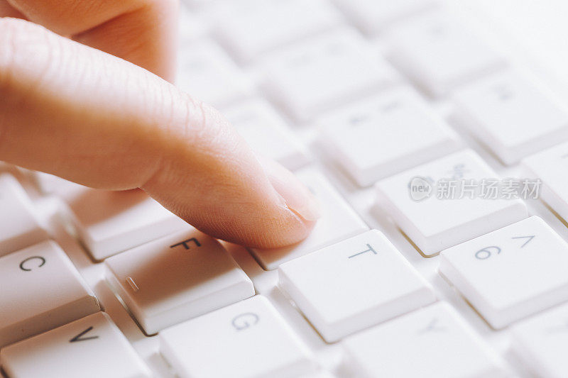 女人的食指在电脑键盘上近距离打字
