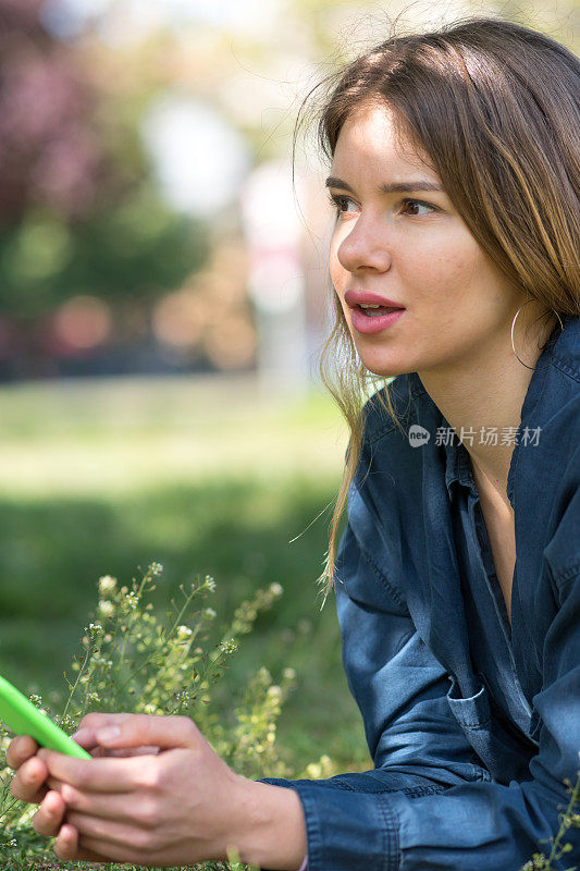 一名年轻女子在公园户外使用智能手机