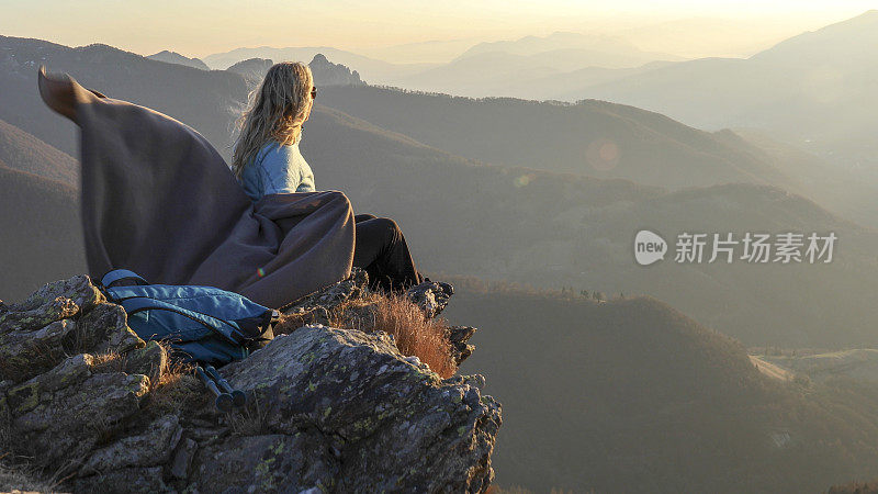 日出时，女人在山脊上休息