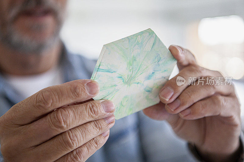 英俊的成熟男子看着回收塑料杯垫的特写