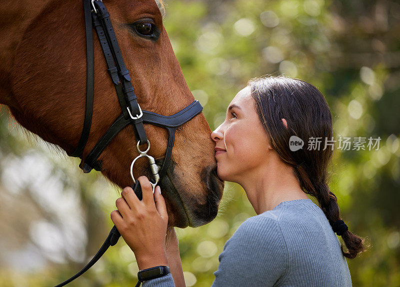 一个迷人的年轻女子和她的马站在森林里