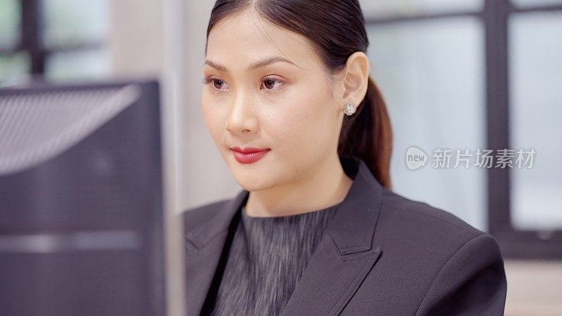 近距离的有吸引力的亚洲商业女性有意向工作在电脑键盘上打字，看着屏幕。认真的女性形象与工作，有自信，领导能力和责任感