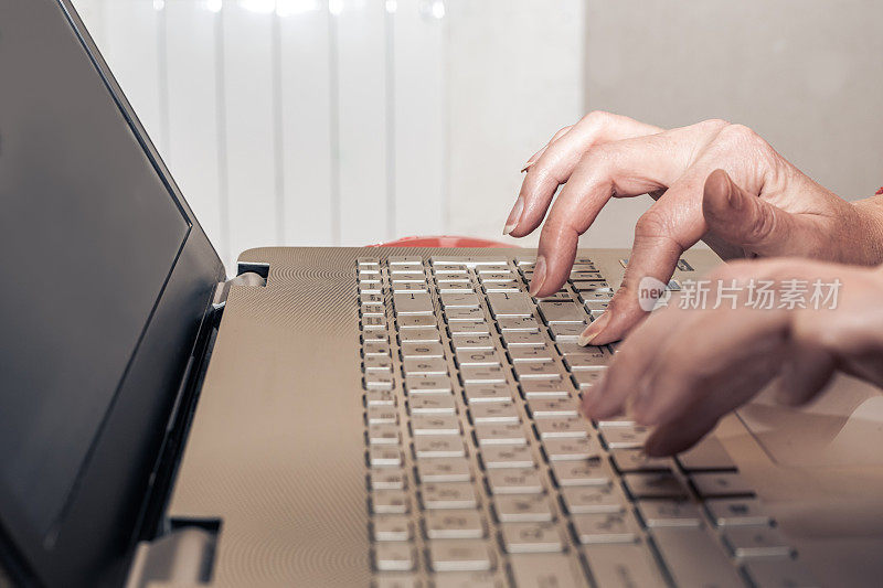 女性在家里用笔记本电脑键盘。在家上学和远程工作