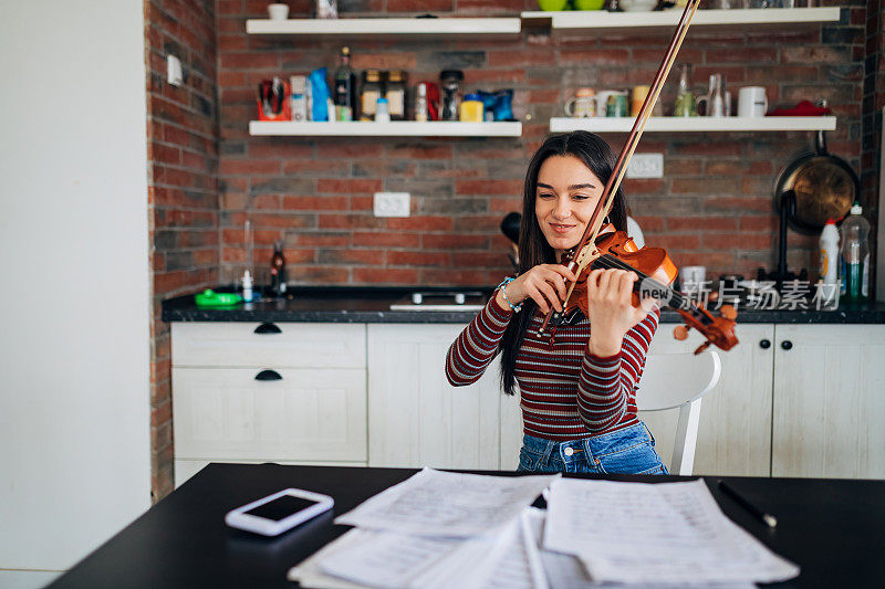 一个思想积极的女小提琴手在家拉小提琴，并乐在其中!