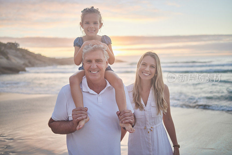 一个白人小女孩被她的爷爷抱着，而她的母亲在日落时走在海滩上的肖像。一家人在夏日的阳光下玩耍