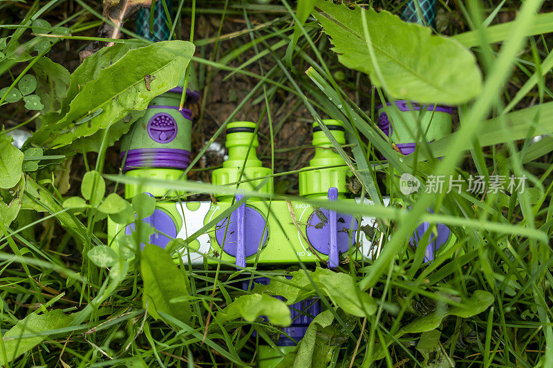 绿色的草地上放着一个用于浇灌水管的塑料分配器。