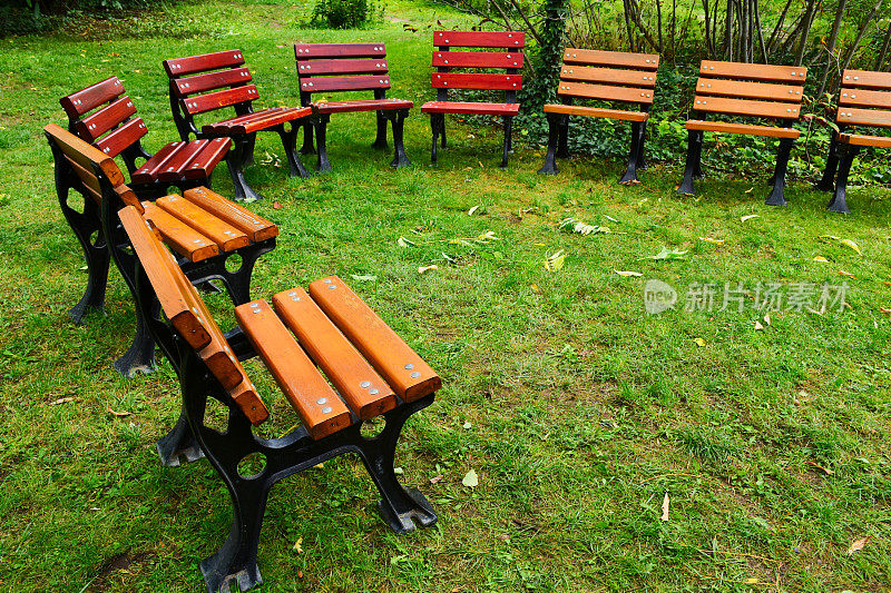 木制和铸铁的花园椅放在绿色的草地上。