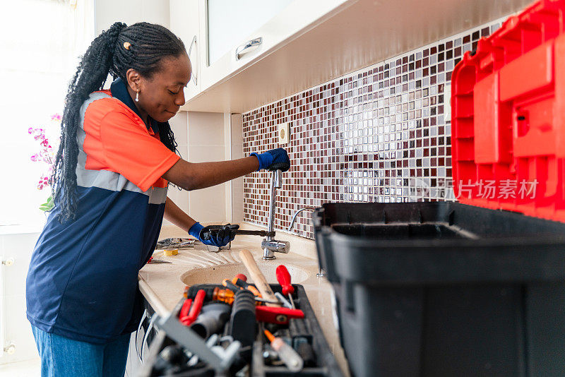 黑人女水管工正在修理一所房子厨房水槽的漏水处