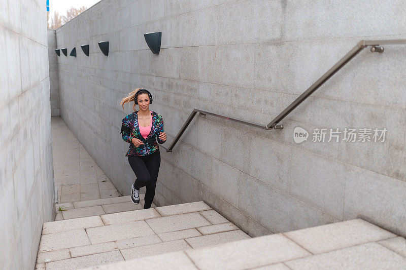 健身年轻女运动员在城市环境中跑步上楼梯