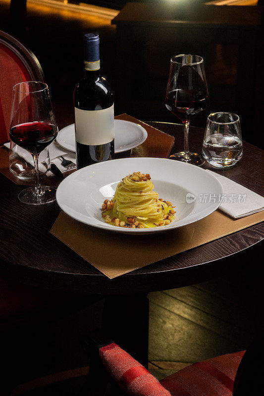 在餐厅餐桌上的意大利干酪面，配有玻璃杯和一瓶葡萄酒