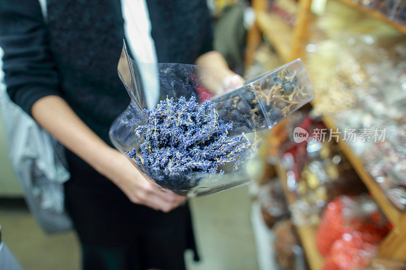 一个成熟的女人手里拿着干花薰衣草继续选择其他干花