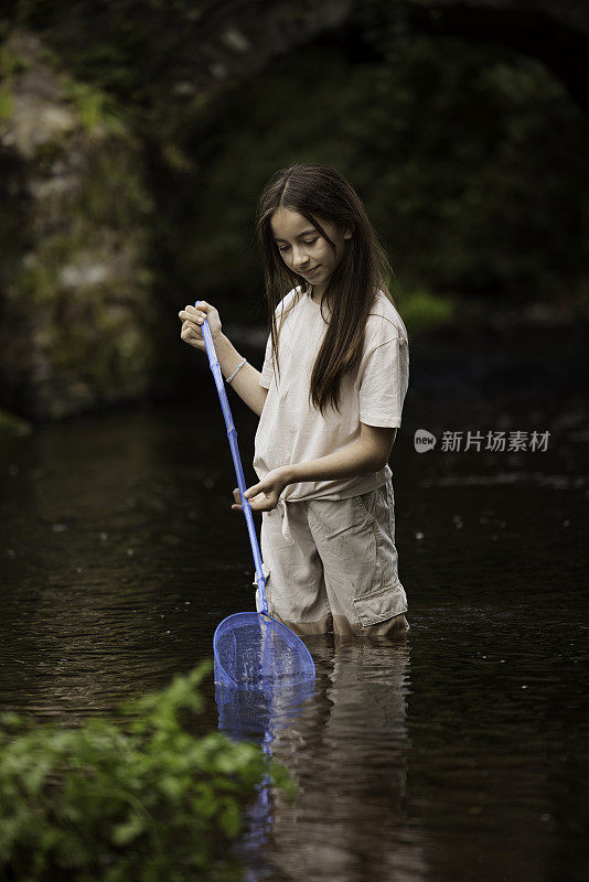 11岁的小女孩在小溪里拿着她的渔网