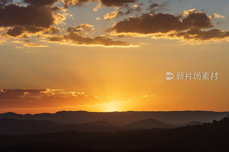 夕阳映衬着金色的天空和起伏的群山