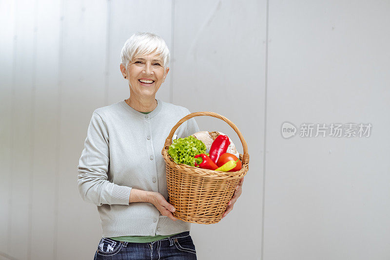 漂亮的老年妇女提着一篮子新鲜食品