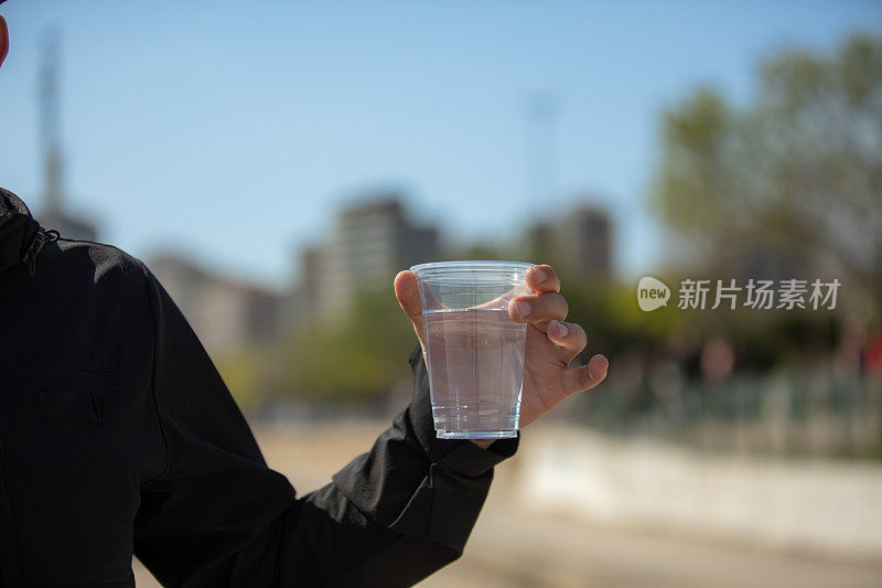 年轻人拿着一个塑料杯。