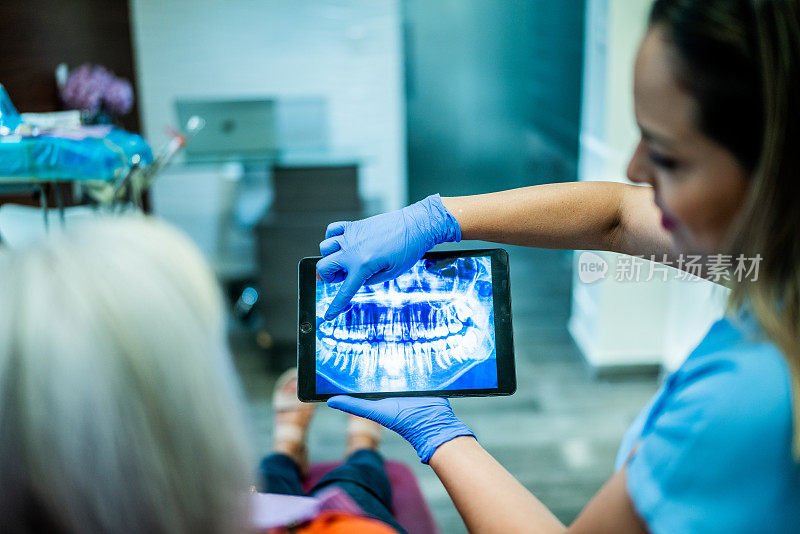 牙医在牙医办公室和病人谈话，给她看x光片