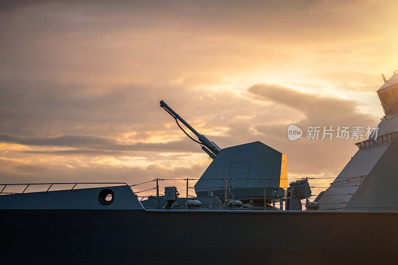 日落时军舰上的军用航母炮塔和武器特写