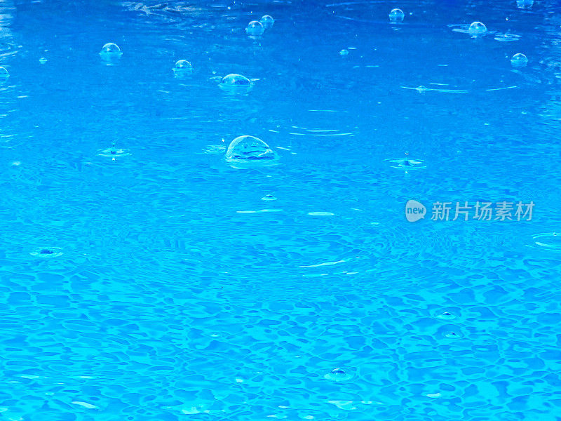 蓝色的水在一个池与雨滴落下-涟漪，泡沫