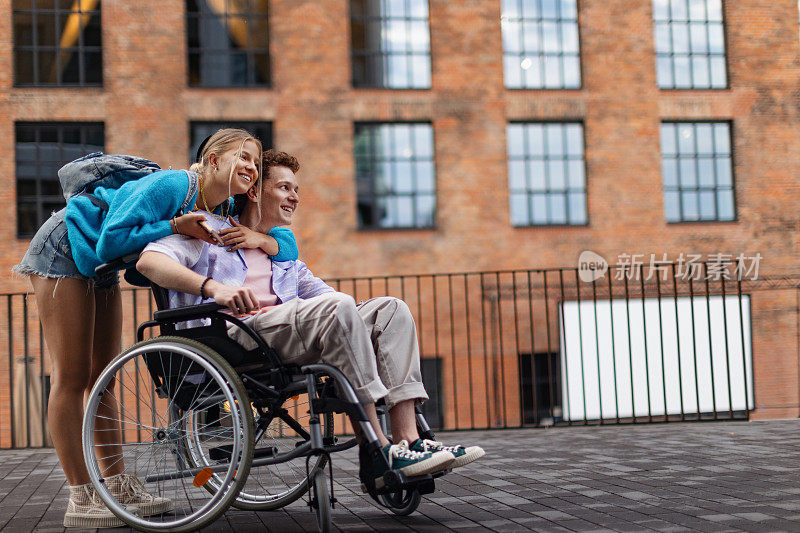 帅气的Z世代男孩和他的女朋友坐在轮椅上。残疾之爱。Z世代的包容、平等和多样性。
