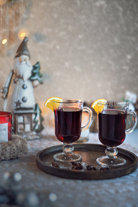 新年餐桌上摆放着精美的玻璃杯，配上热红酒，散发着新年的气息，背景是圣诞老人的黄花圈