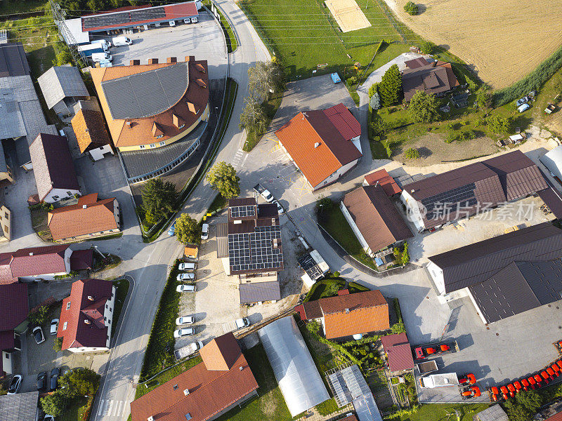 住宅小区鸟瞰图，屋顶上有房屋、道路和太阳能电池板，展示了郊区的发展和可再生能源的使用。